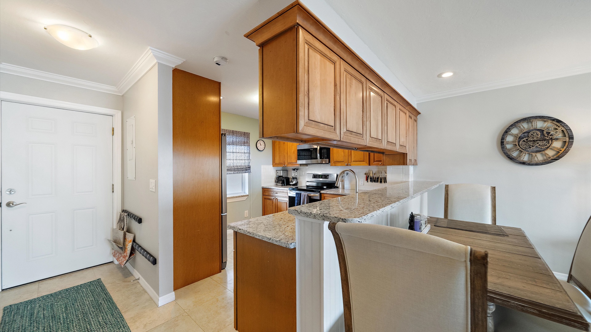 The kitchen opens toward the dining and living areas, giving the home a comfortable, connected layout. Granite counters and warm wood cabinetry complement the relaxed coastal interiors.
