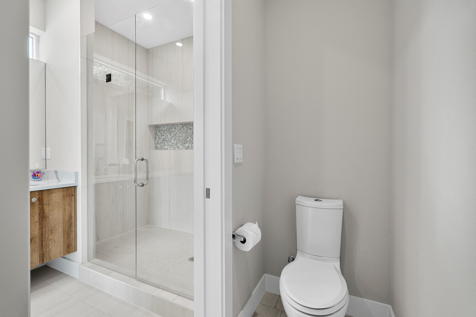 A crisp, contemporary bathroom offering your own bright shower enclosure with beautiful tile accents, a private toilet nook, and a stylish vanity ready for your morning routine.