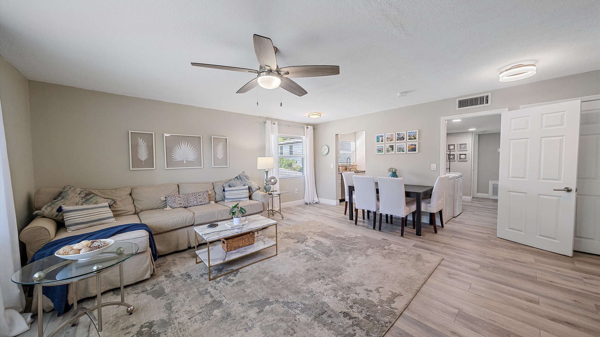 Relax in your open-concept living and dining area, where soft neutral tones and comfortable seating invite you to unwind. Natural light streams through the windows while a ceiling fan keeps the space cool and inviting.