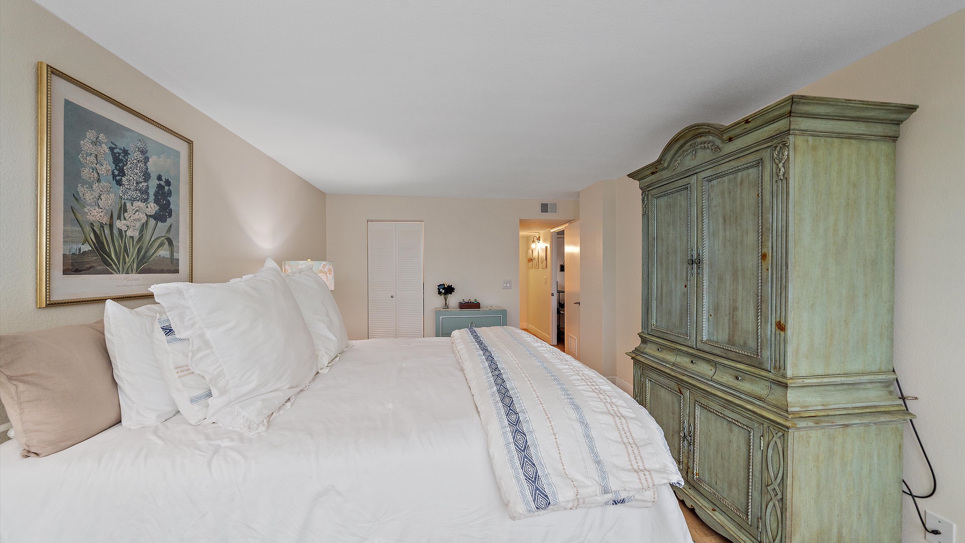 Settle into your peaceful bedroom featuring crisp white linens, elegant artwork, and charming vintage-style furnishings for a restful night's sleep.