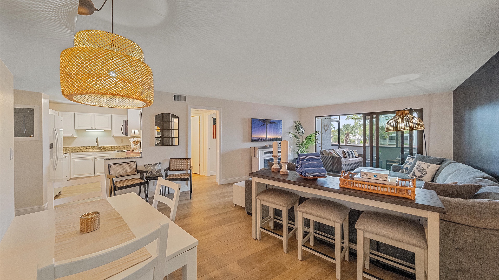 Relax in your spacious open-concept living area with modern furnishings, stylish wicker lighting, and seamless flow between the kitchen and lounge spaces.