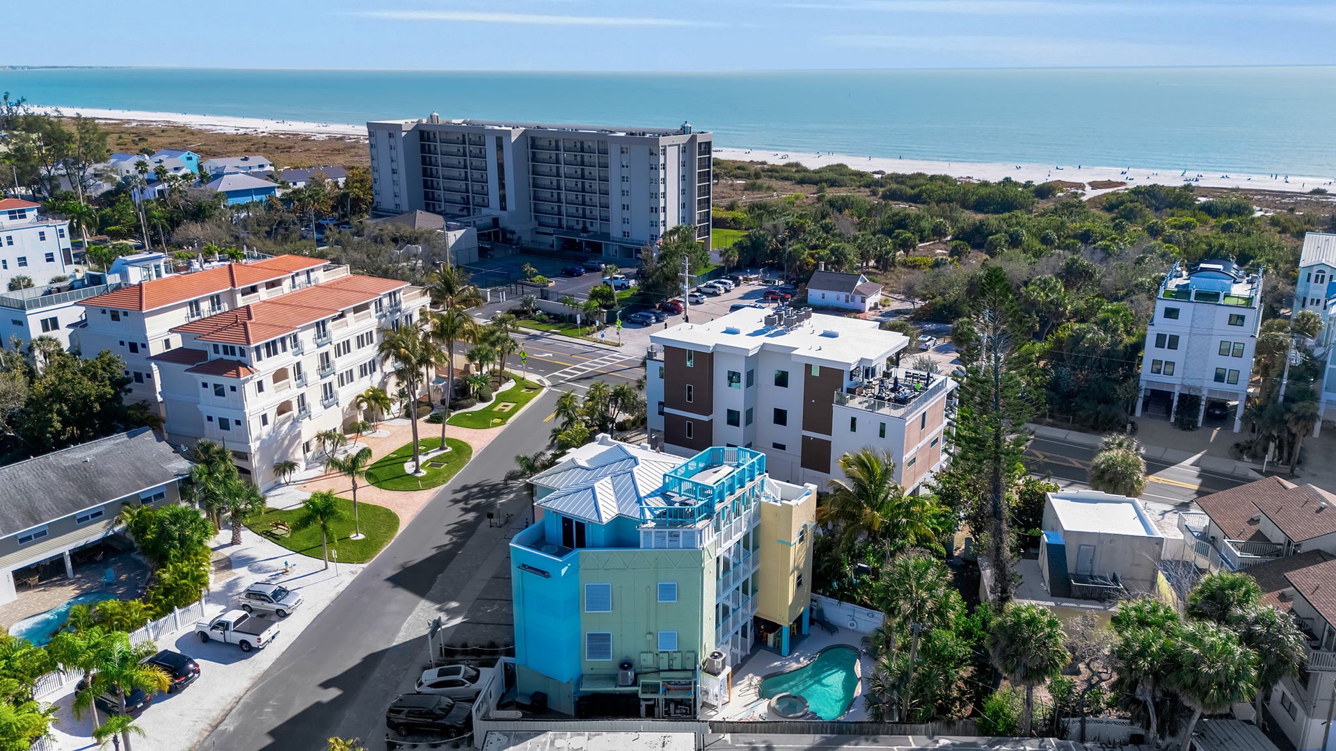 An aerial view capturing the beachfront property nestled among coastal neighborhoods, with direct access to pristine white sands and the Gulf waters just steps away.