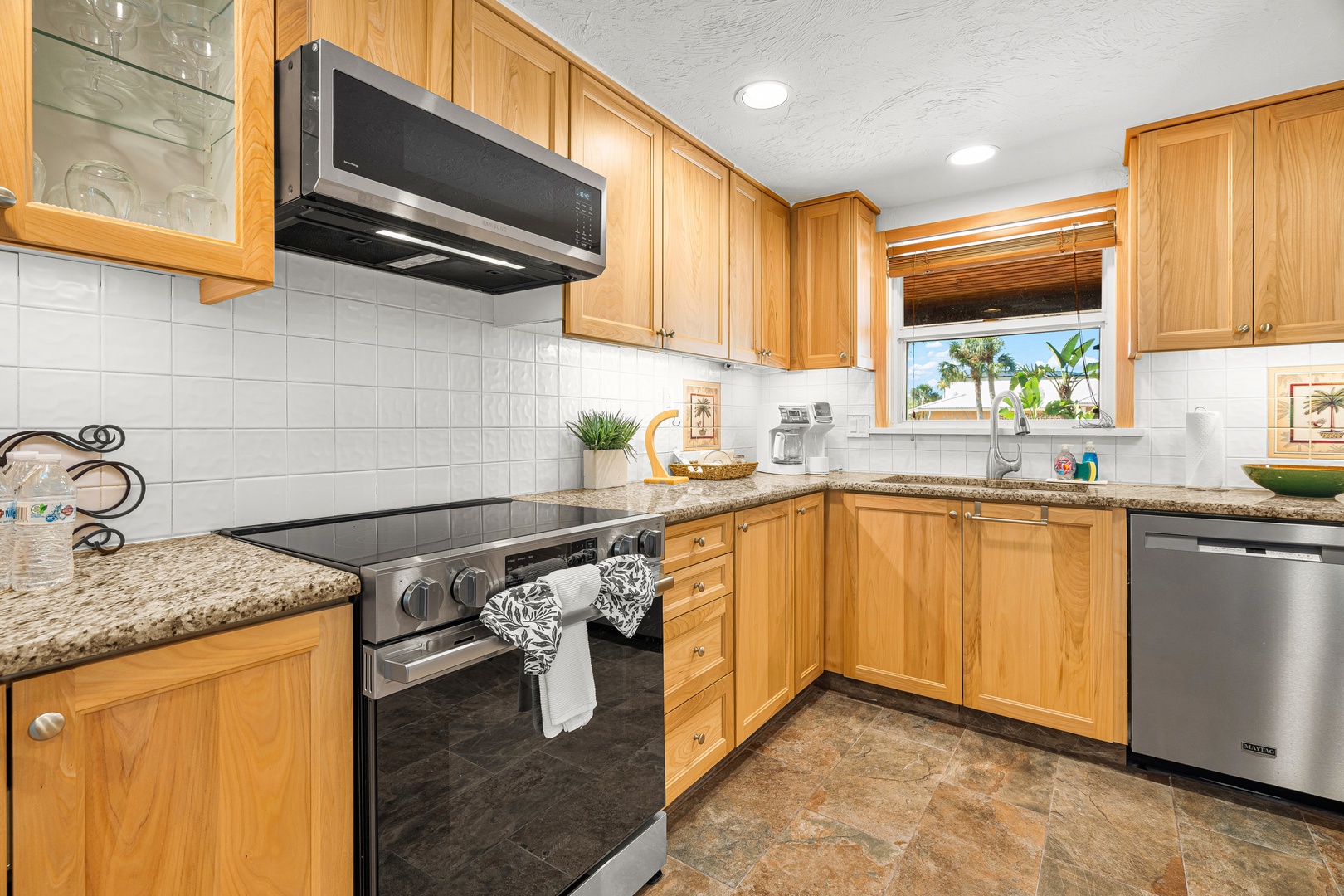 Fully stocked and equipped spacious kitchen with granite countertops and stainless steel appliances.