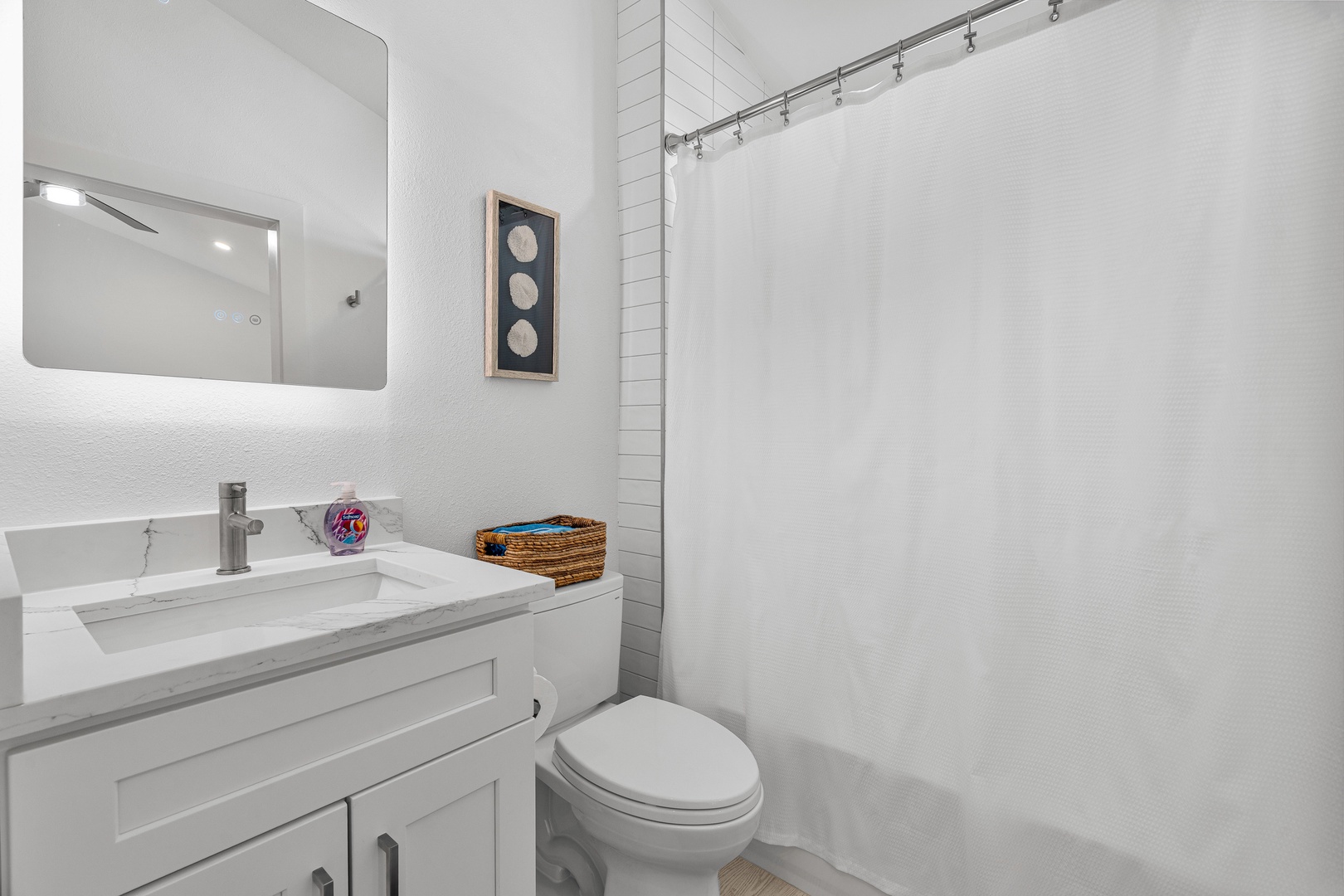 Freshen up in this bright, modern bathroom with crisp white finishes, thoughtful coastal touches, and a spacious walk-in shower for your comfort.