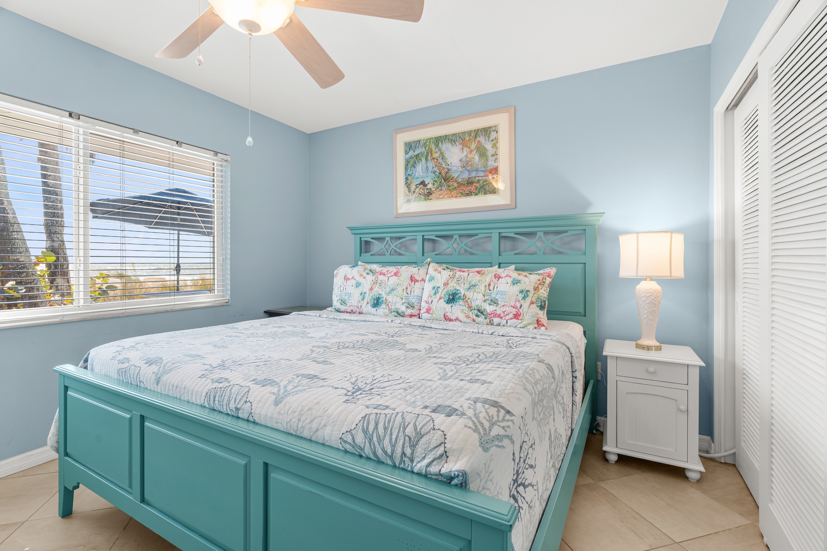 Drift off in your coastal-inspired bedroom, where soft blue walls and tropical artwork create a serene retreat with gentle ocean breezes flowing through.