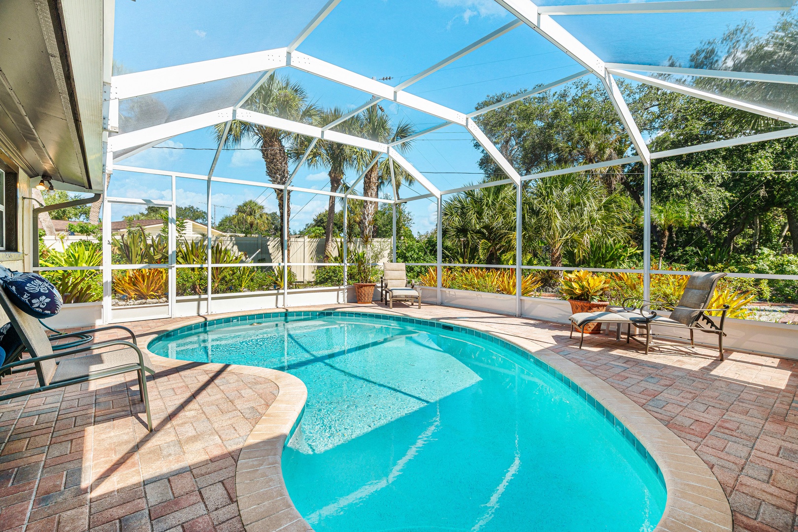 Private heated screened-in pool surrounded by lush tropical landscaping.