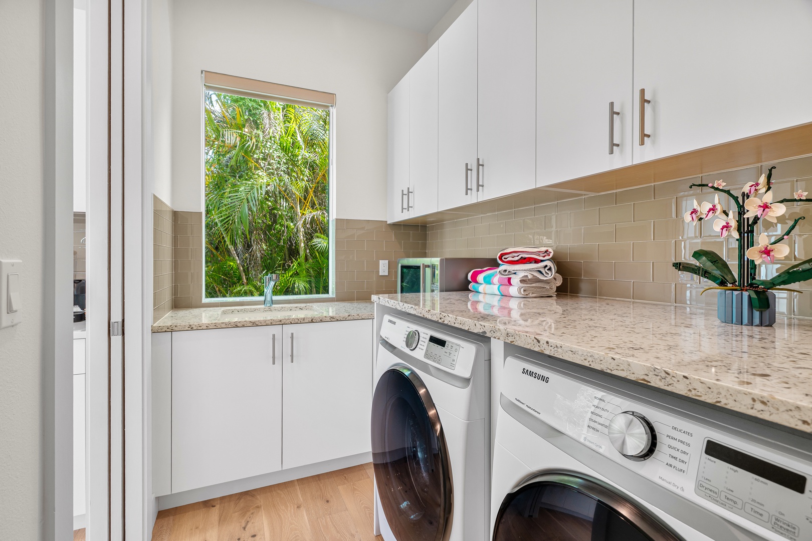 A bright, well-appointed laundry room awaits with modern appliances and tropical garden views to make chores feel effortless.