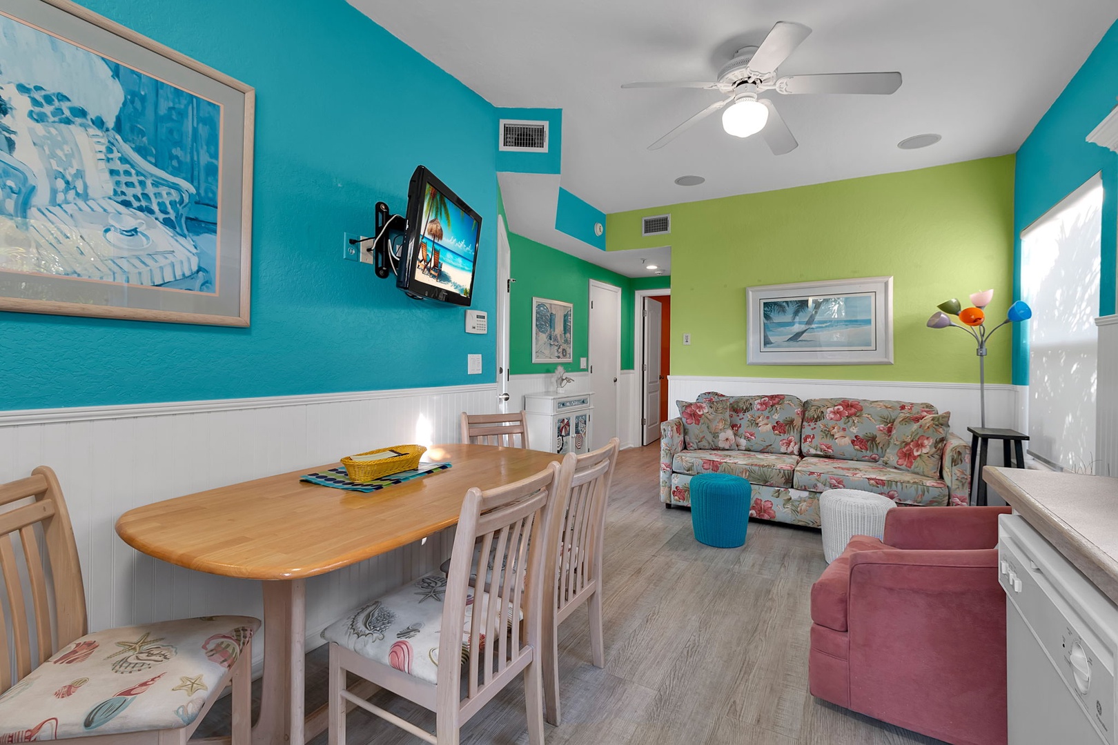 Step into your vibrant coastal retreat, where bold turquoise and lime walls create a cheerful atmosphere. Relax on the floral sofa, gather around the dining table, and enjoy the bright, airy open layout that makes you feel right at home.