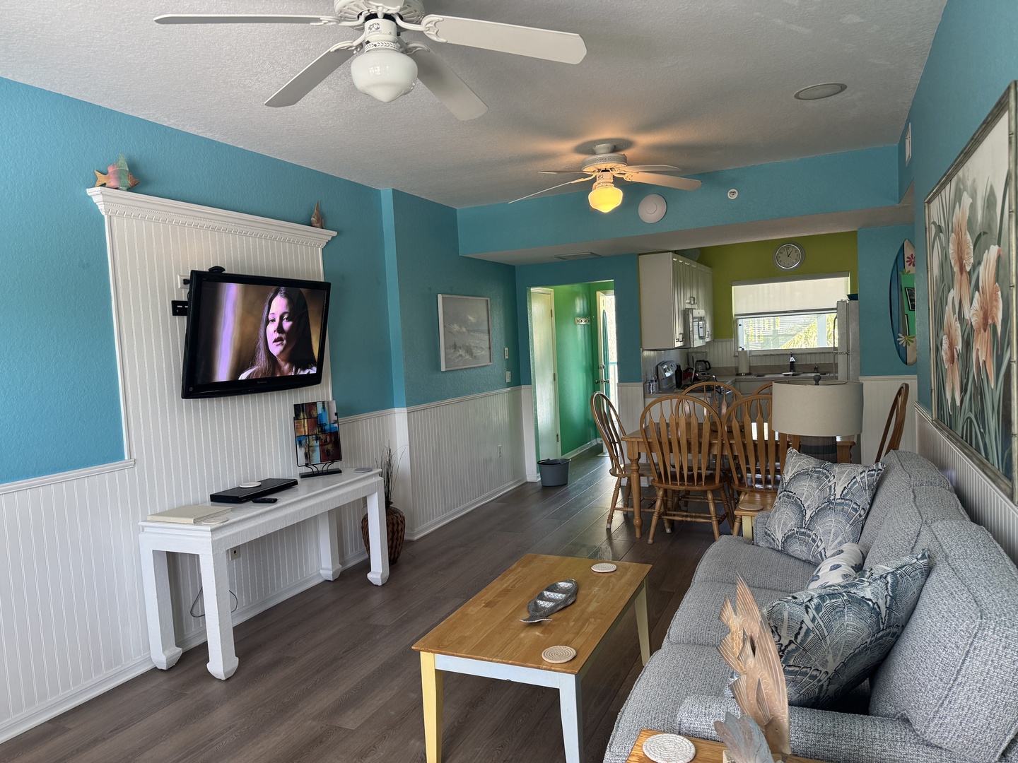 Settle into your bright, open-plan living space where cheerful coastal hues and ceiling fans keep you comfortable. The living room flows into your dining area and fully equipped kitchen, perfect for easy meals and relaxed evenings together.