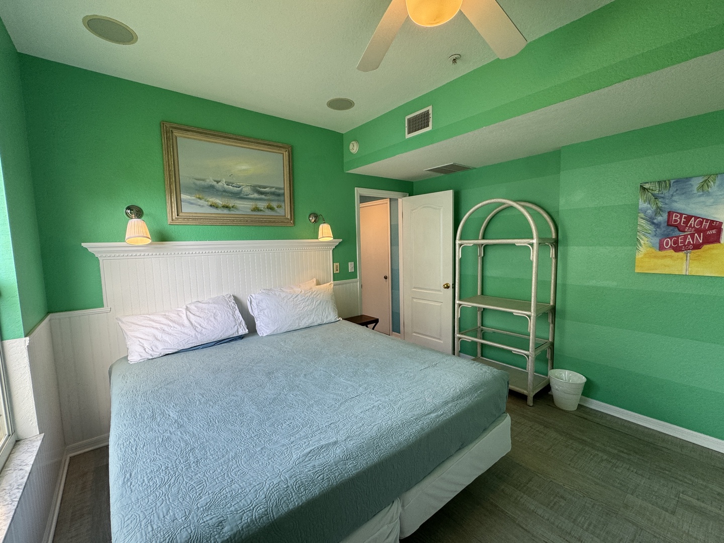 Settle into your soothing coastal sanctuary, where soft seafoam walls and a plush bed invite peaceful slumber beneath a gentle ceiling fan.