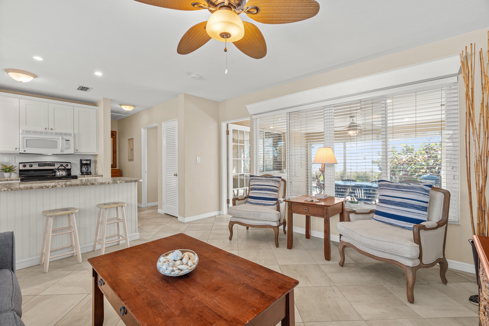 Your bright, airy living space flows seamlessly into the kitchen, where coastal breezes through large windows create the perfect tropical retreat.