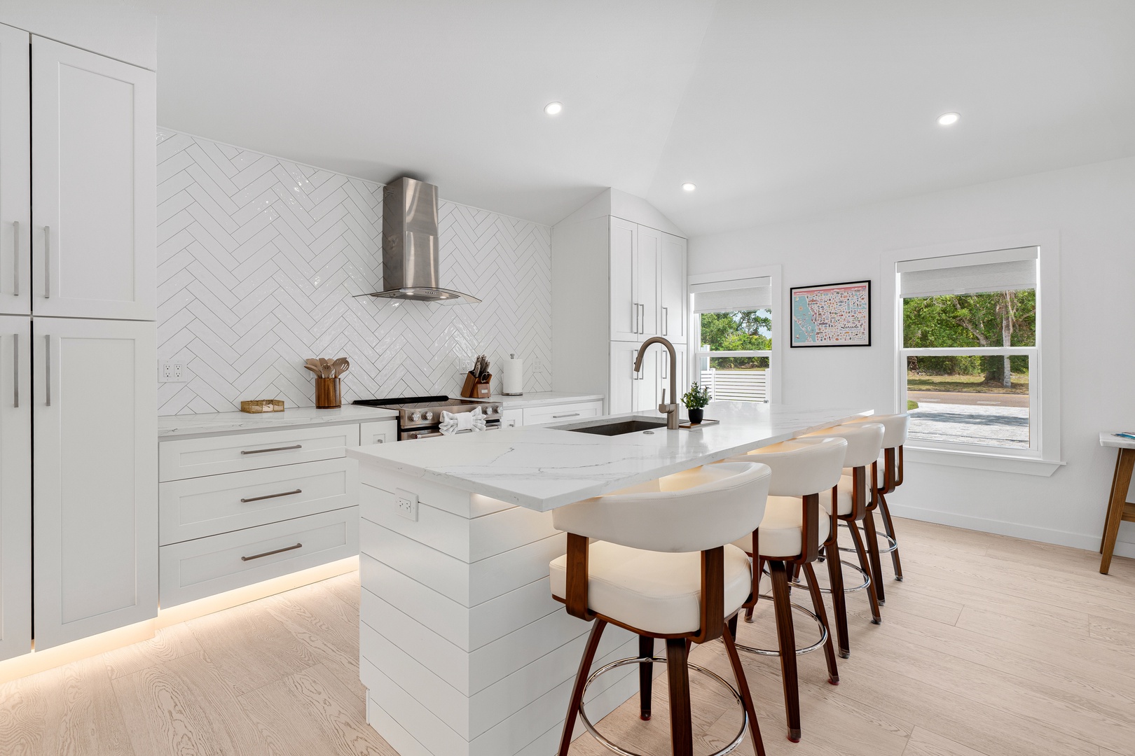 Picture yourself preparing a meal in this bright, modern kitchen with sleek white cabinetry, marble countertops, and a spacious island perfect for gathering with friends or family.