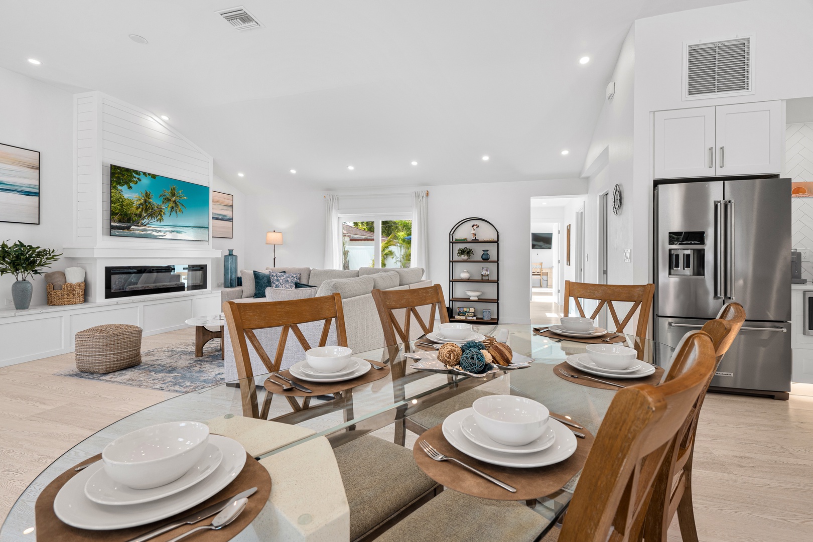 Gather around this bright, open living space where modern comfort meets coastal charm. Your vacation begins at the dining table with sleek decor, flowing into a cozy lounge with a fireplace and tropical views.