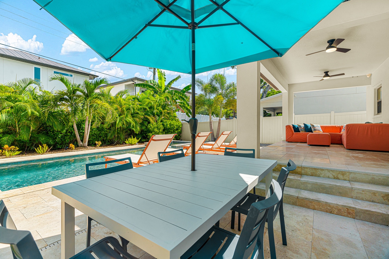 Dine outside in total comfort at your private poolside table, shaded by a turquoise umbrella. Lounge chairs beckon you to soak up the sunshine, while lush palms and a relaxing covered living area complete your tropical escape.
