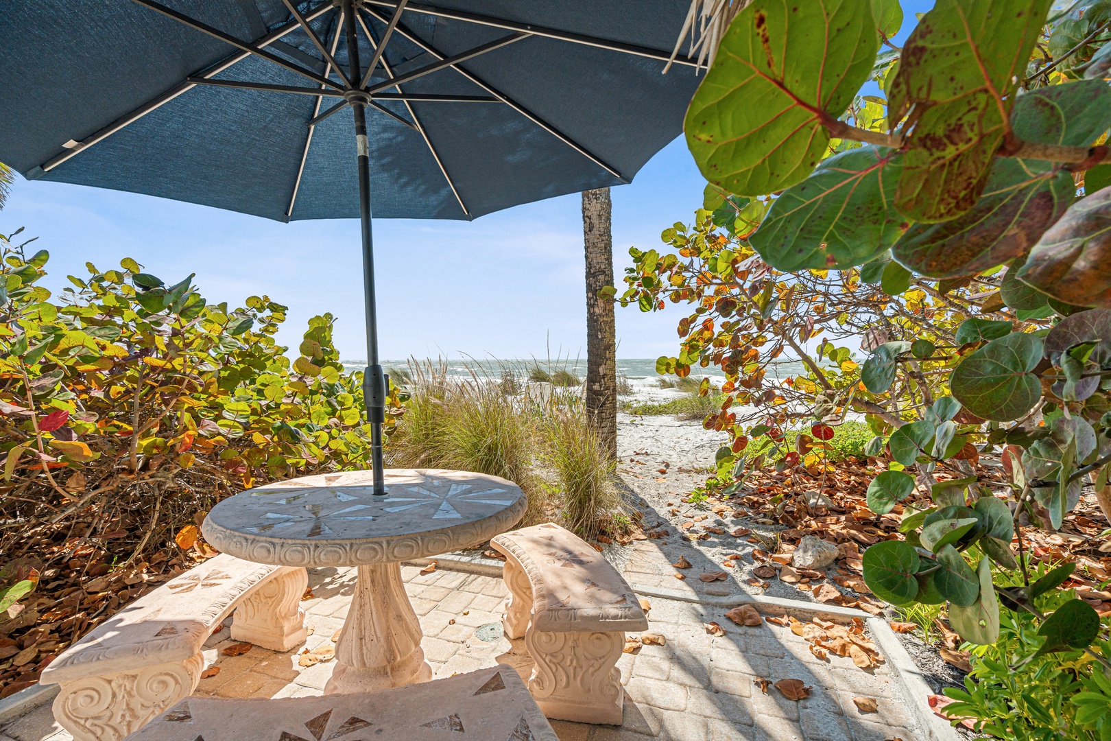 Your private beachfront dining nook awaits, where ornate stone seating and shade create the perfect spot for morning coffee or sunset cocktails.