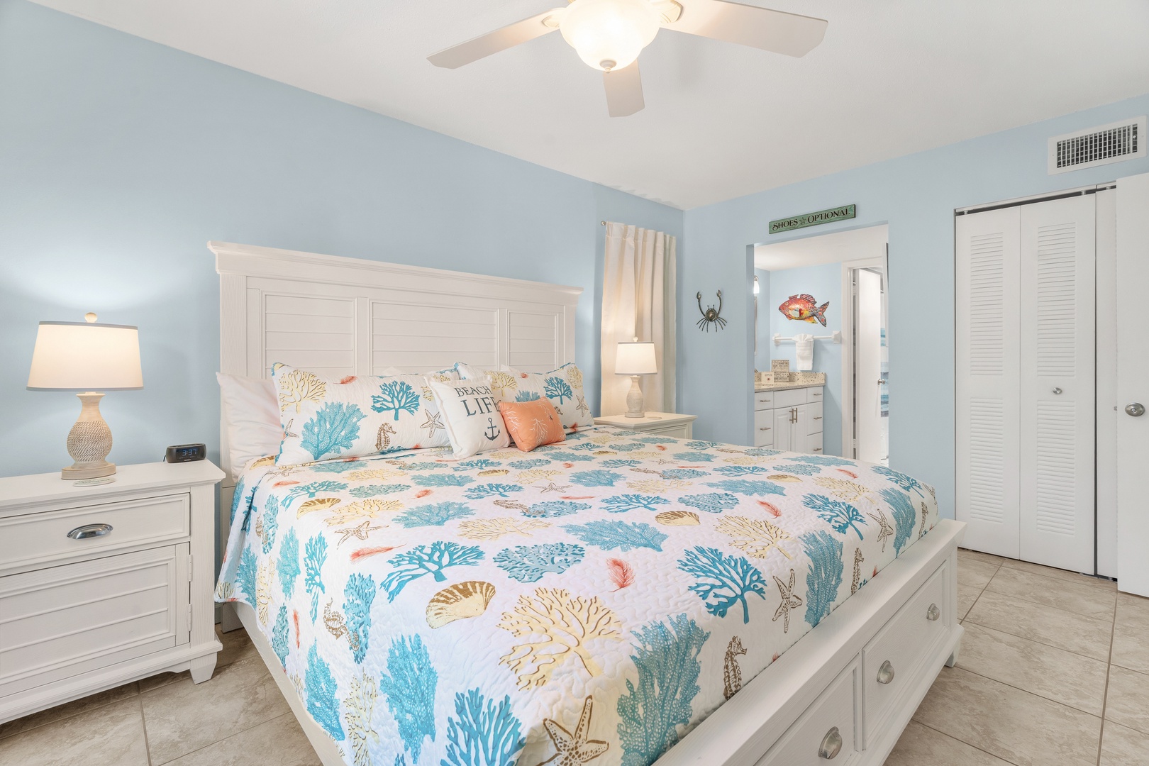 Bright coastal primary bedroom with King bed, fresh hotel-style linens, and ensuite bathroom.
