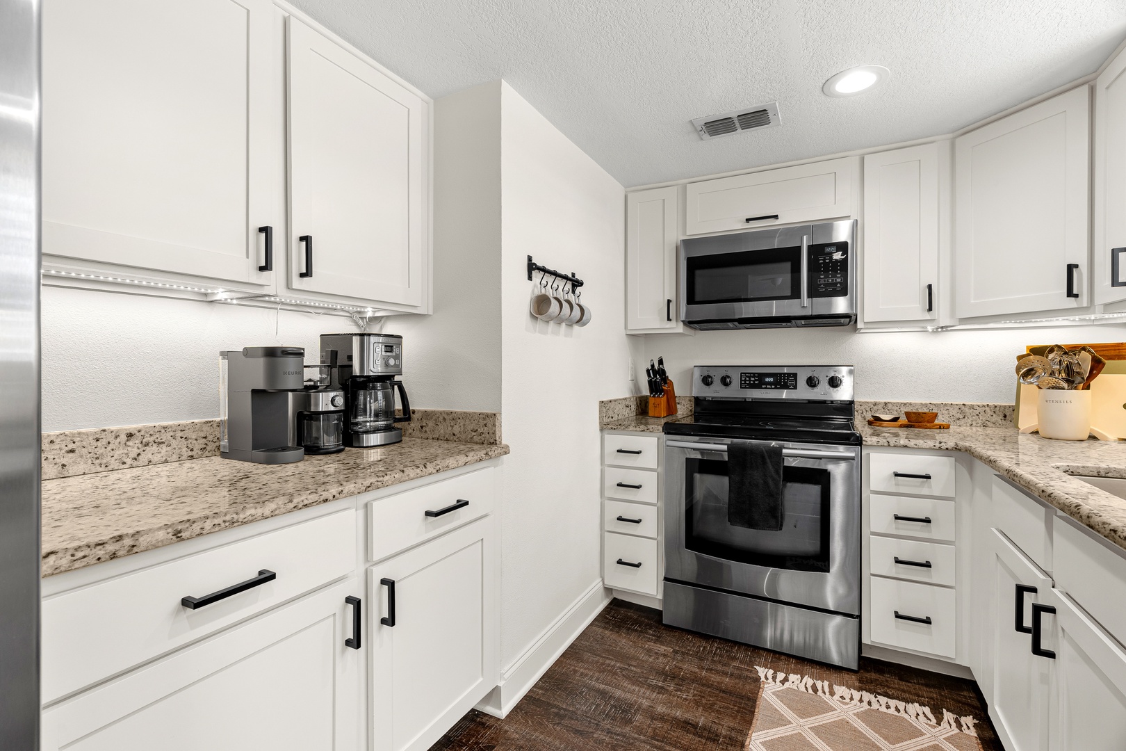 Your fully equipped kitchen features granite countertops, stainless appliances, and all the essentials for preparing meals during your stay. Bright cabinets and under-lighting create a welcoming space.
