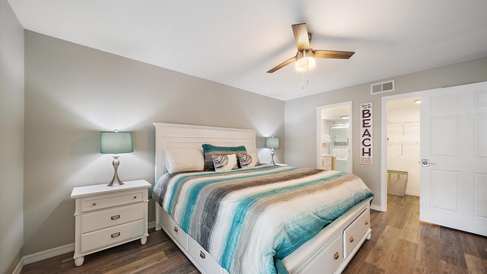 Slip into your serene primary bedroom with its plush bed dressed in coastal-inspired linens, soft lighting, and that gentle ceiling fan keeping you cool all night long.