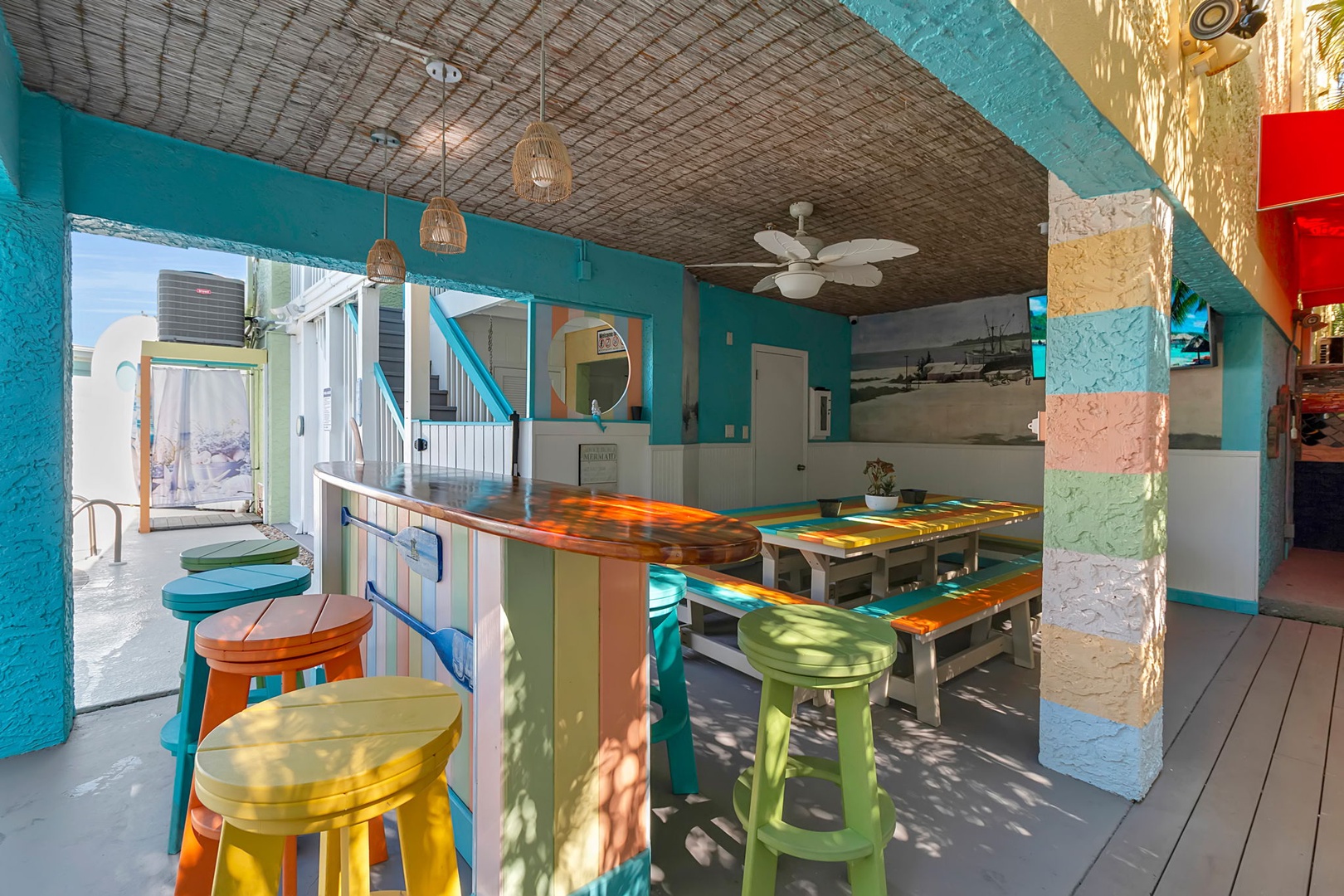 Vibrant communal space with colorful bar seating invites you to gather, share stories, and soak up the tropical atmosphere bathed in natural light.