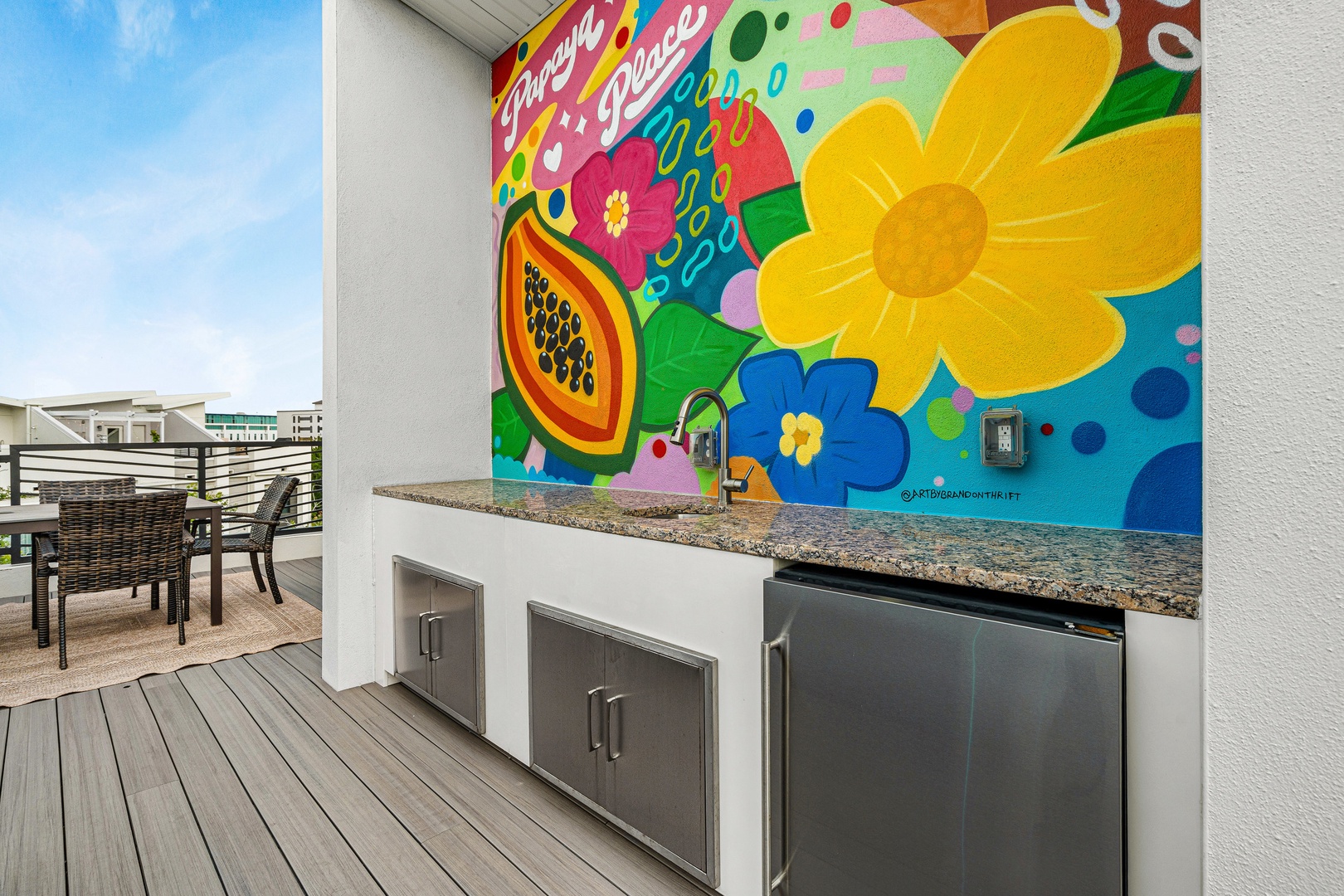 Grill your favorite meals at the outdoor BBQ station with vibrant tropical artwork and nearby patio seating for easy entertaining.