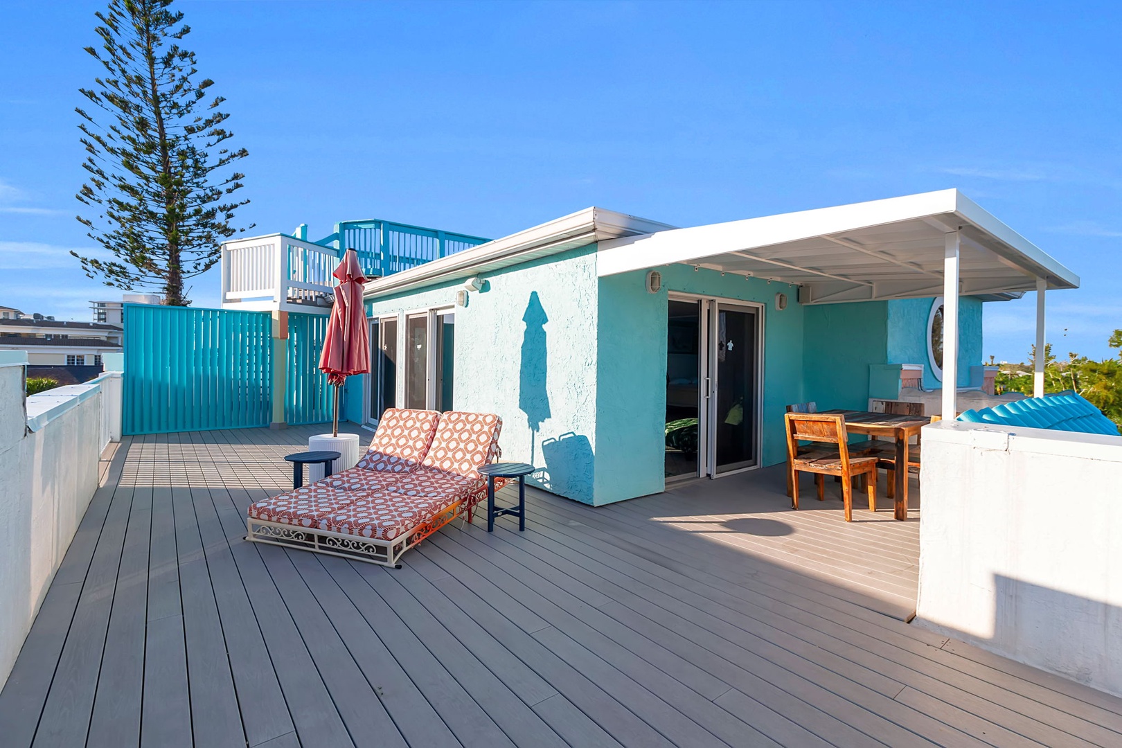 A spacious rooftop deck with lounge chairs and dining under a shaded pergola. Breathe in the ocean breeze and soak up the sun in your own coastal haven.
