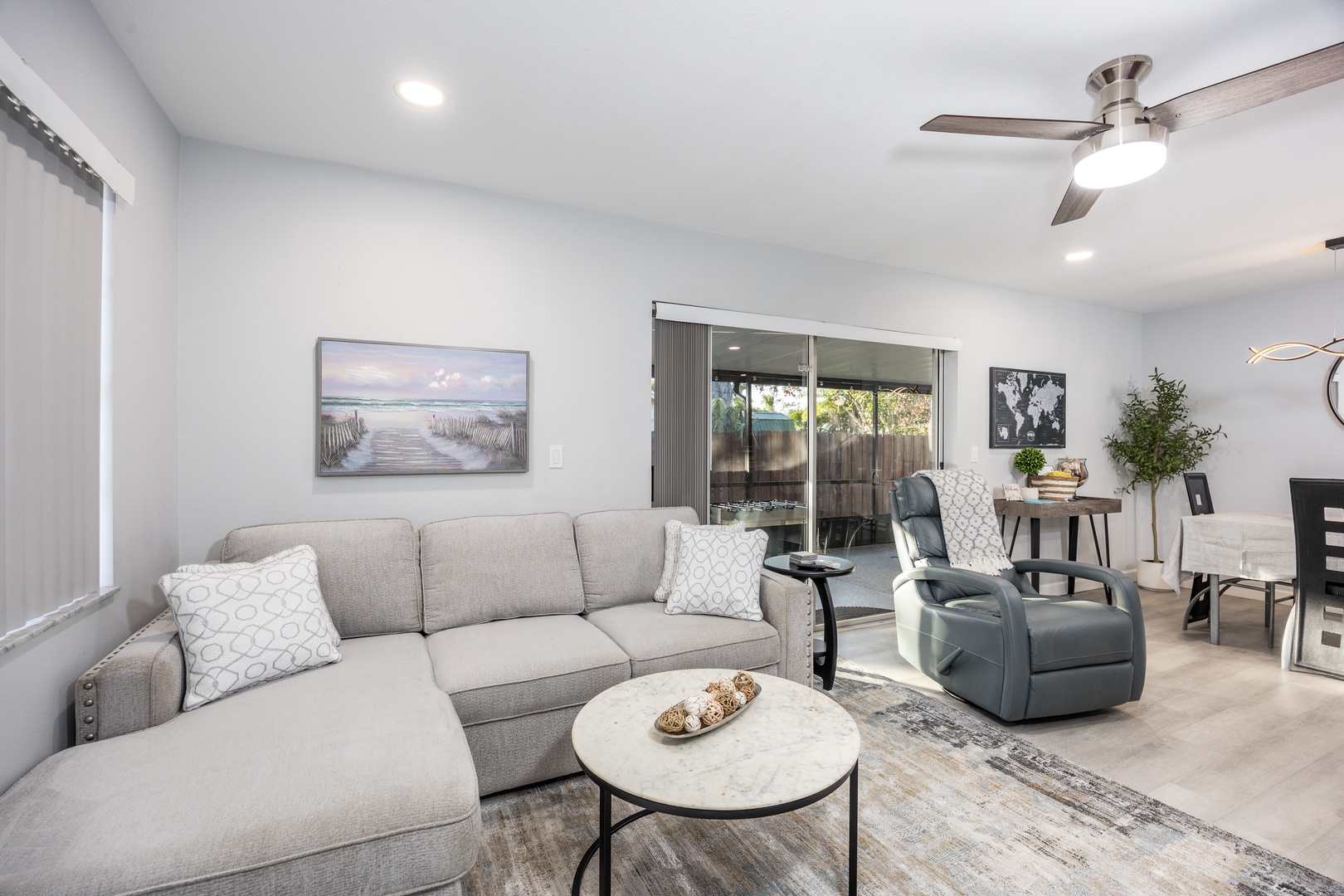 Settle into your spacious living room with plush sectional seating, where coastal artwork and modern touches create the perfect space for relaxation.