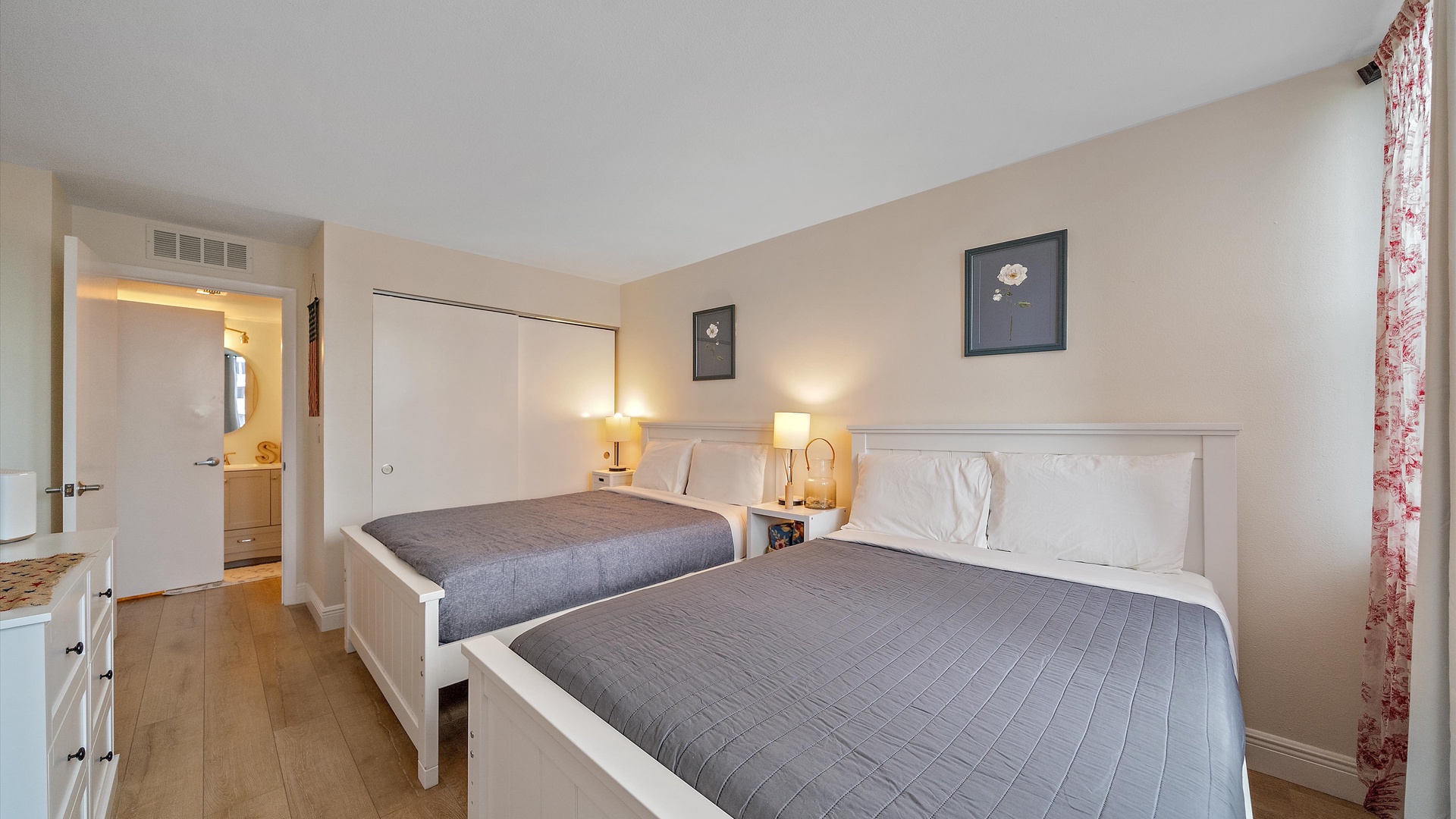 Relax in your comfortable bedroom featuring two queen beds with premium linens, bedside lighting, and warm coastal decor for a peaceful night's sleep.