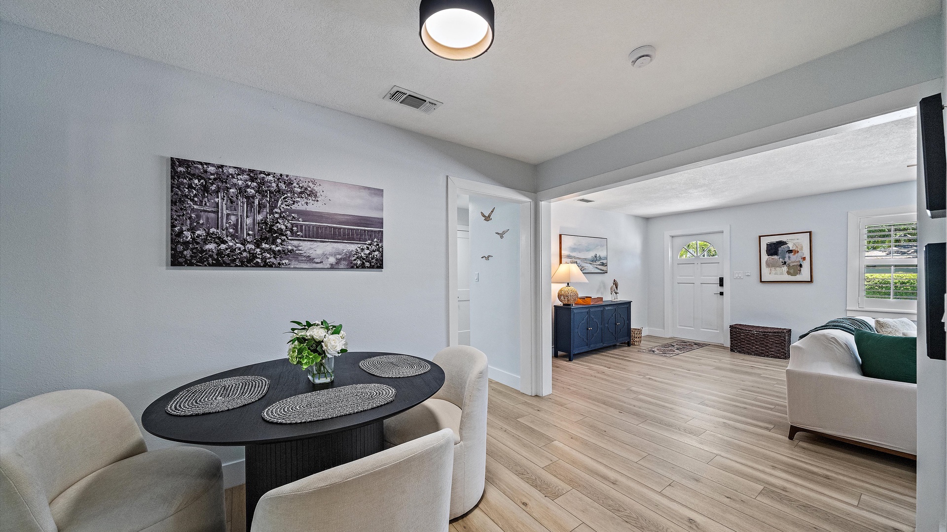 Step into your bright, open-concept living space where pale wood floors and crisp white walls create a calming retreat. The dining area flows seamlessly into your inviting lounge, perfect for unwinding after exploring the area.