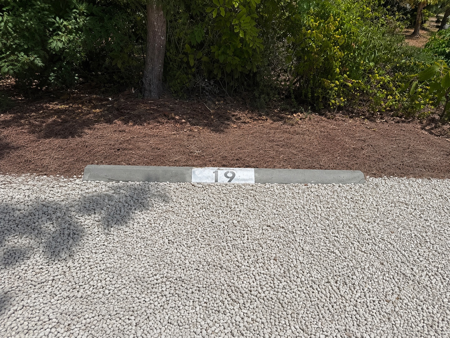 A private parking space is reserved for guests, bordered by lush greenery that frames the property's tranquil surroundings.