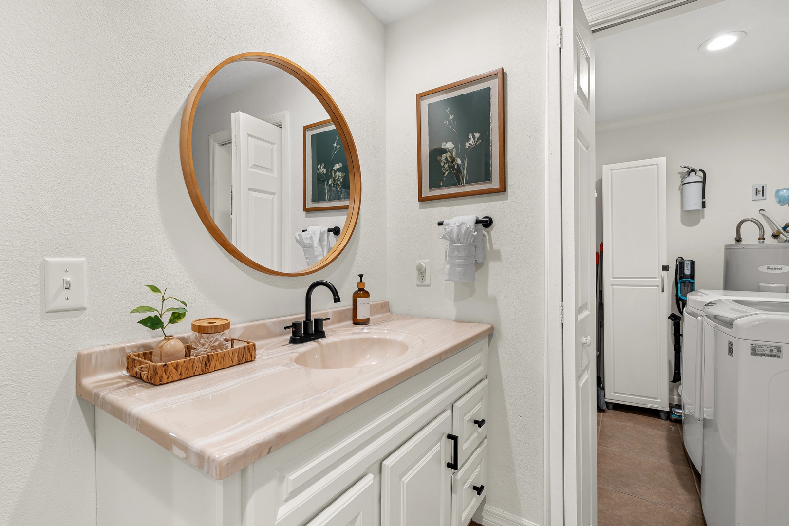 Step into this serene bathroom, where a stylish round mirror and botanical artwork set a calming tone. Fresh towels and thoughtful touches await your arrival.