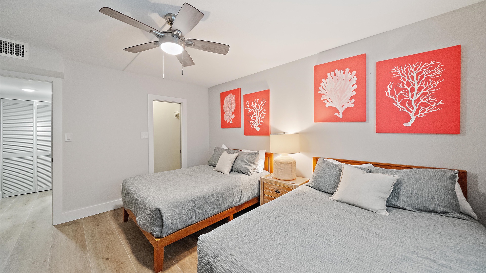 Relax in your coastal-themed bedroom featuring twin beds with soft gray linens and vibrant coral artwork creating a soothing seaside atmosphere.