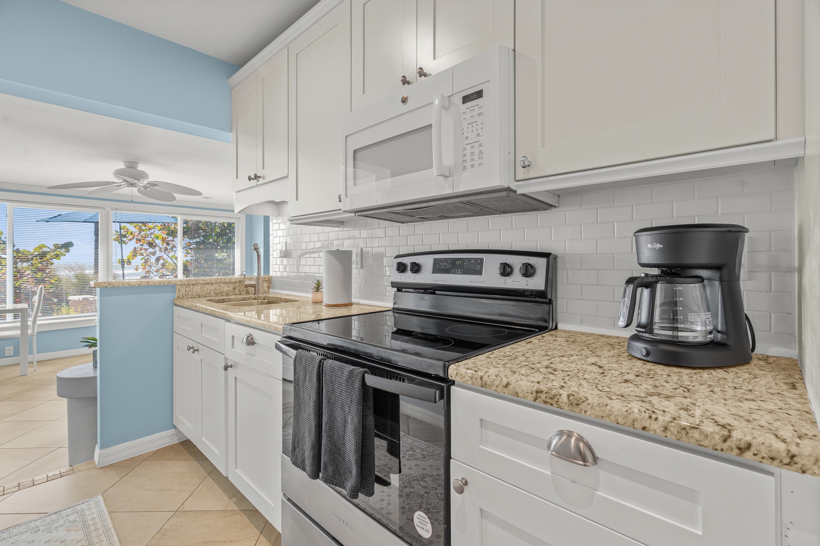 Step into your bright, fully-equipped kitchen with granite counters, modern appliances, and ocean breezes through sunny windows.