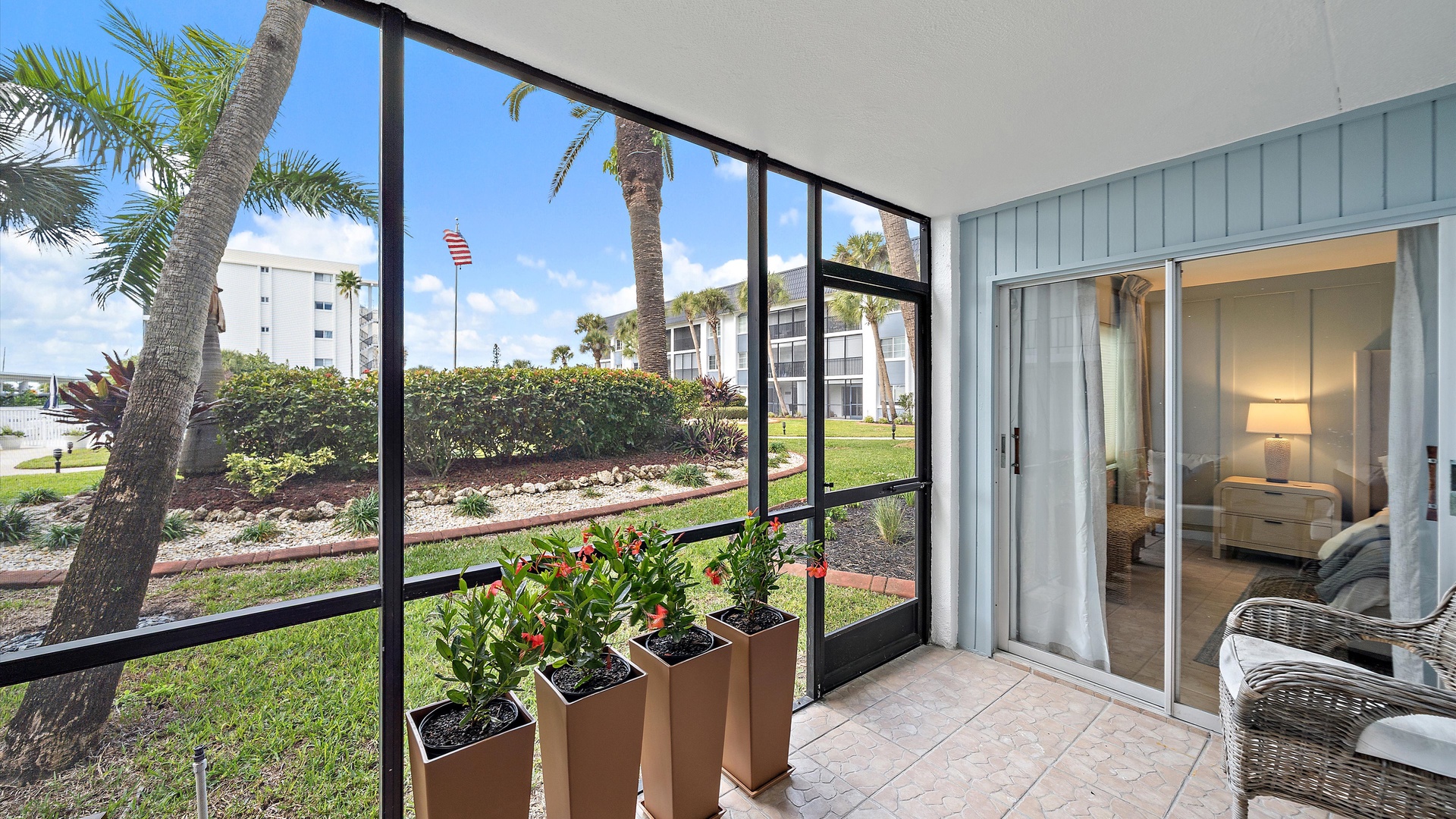 Your screened balcony offers peaceful moments with tropical plants while you enjoy garden views and glimpses of neighboring buildings.