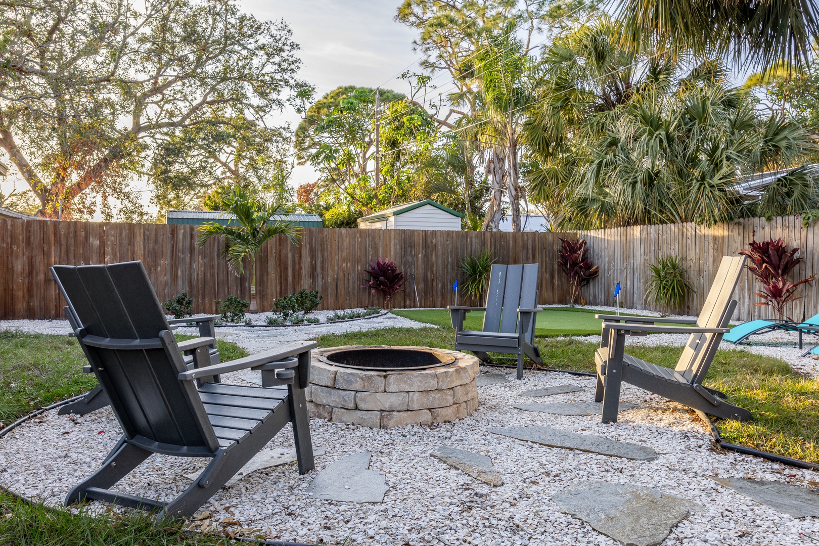 Gather around your private fire pit for cozy evenings under swaying palms in this tropical backyard retreat.