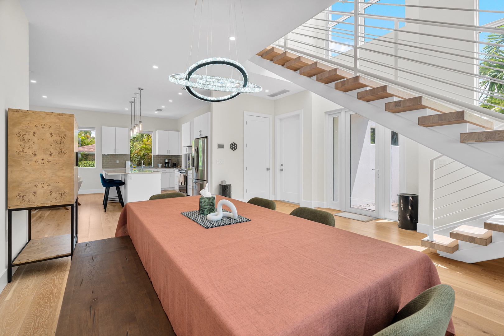 Step into your open-concept living space where natural light floods the modern dining and kitchen area. The floating wooden staircase adds architectural elegance to your relaxing retreat.