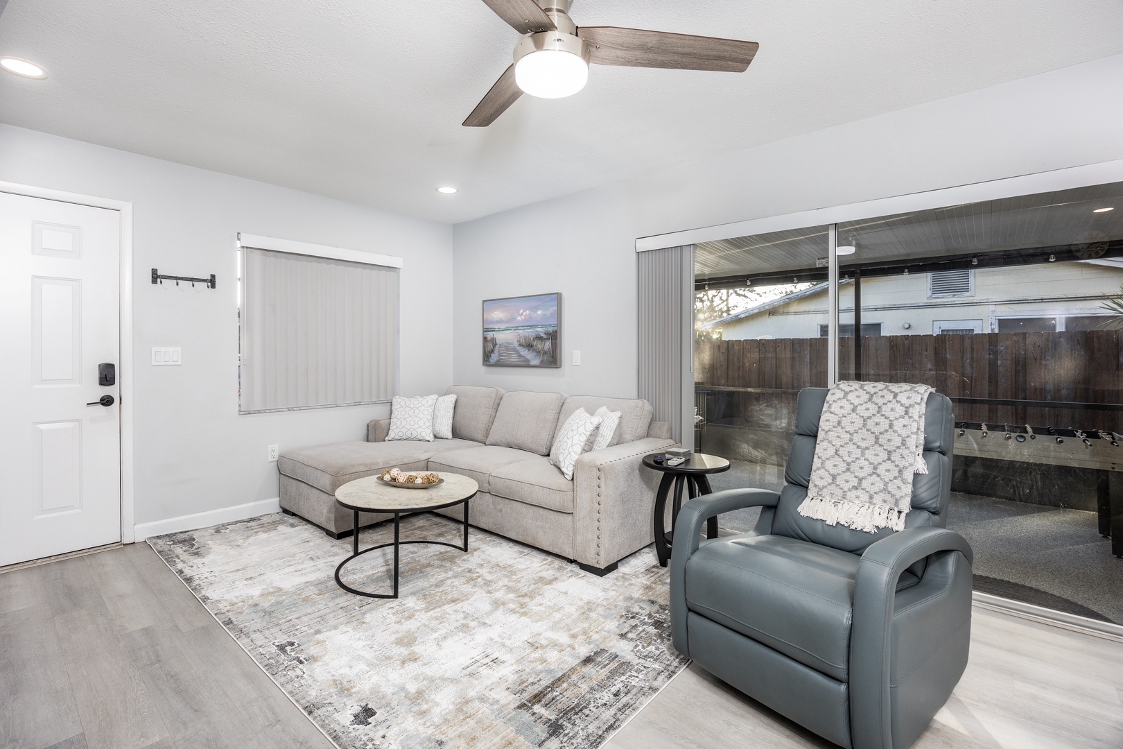 Relax in your stylish living room with plush seating, modern ceiling fan, and sliding doors that open to your private outdoor space.