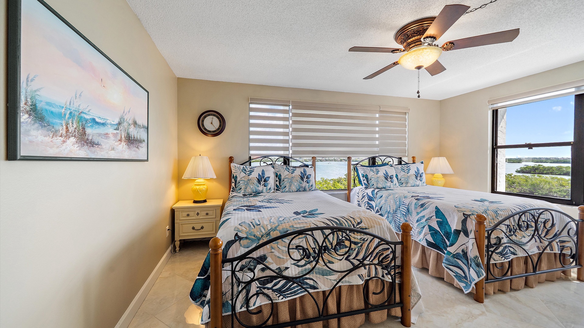 Wake up to breathtaking water views in your coastal-themed bedroom, where two queen beds invite restful nights beneath the gentle ceiling fan breeze.