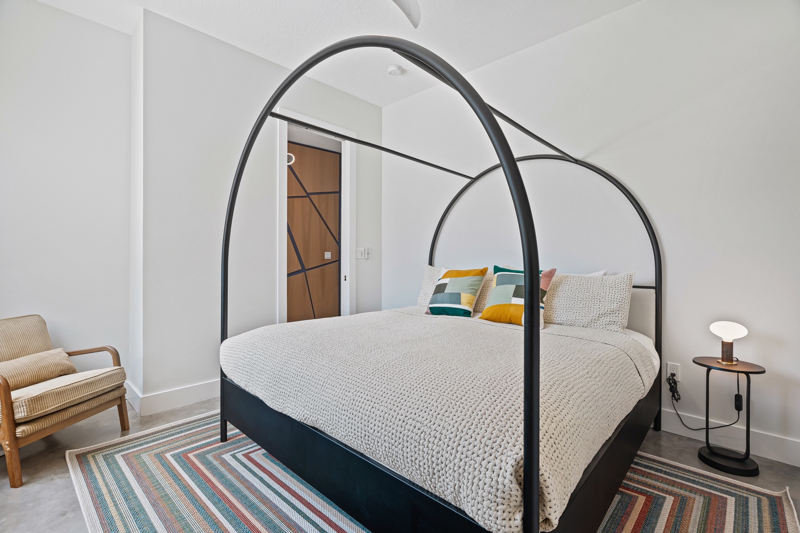 Unwind in your beautifully styled bedroom, featuring a striking canopy bed dressed in soft linens, plush accent pillows, and a cozy armchair perfect for curling up with a book.