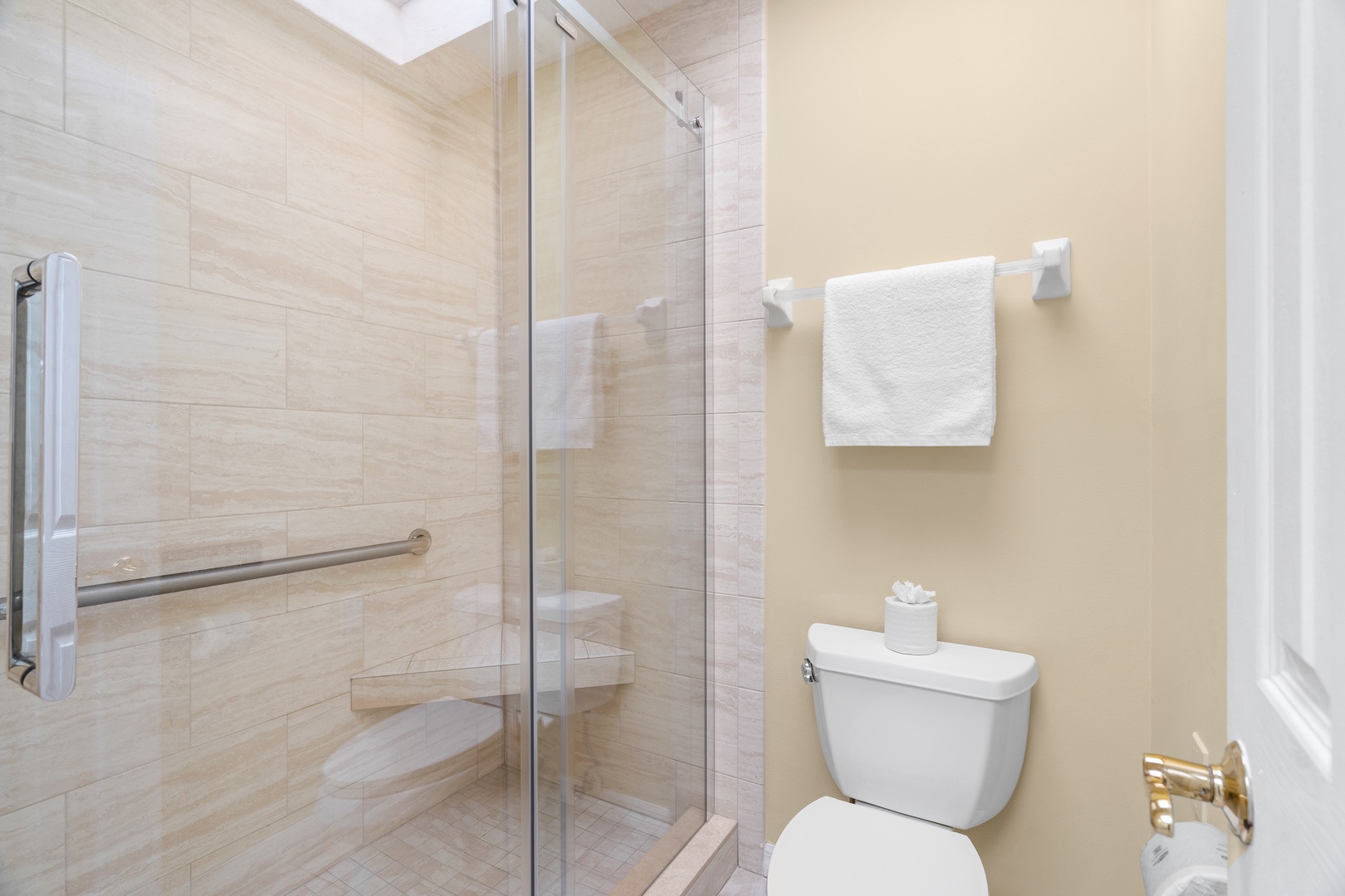 Step into your pristine bathroom featuring a spacious walk-in shower with safety grab bars and fresh towels waiting for you.