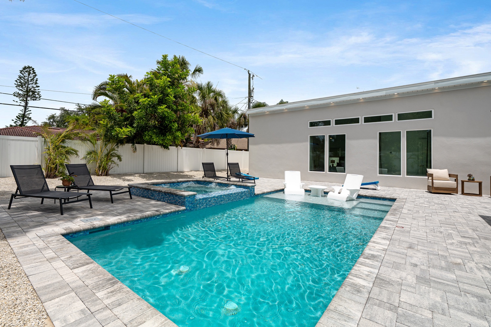 Imagine yourself lounging poolside in this private backyard paradise, where sun-soaked days and tropical breezes await. Your own sparkling pool features a tanning ledge, perfect for relaxation under swaying palms.