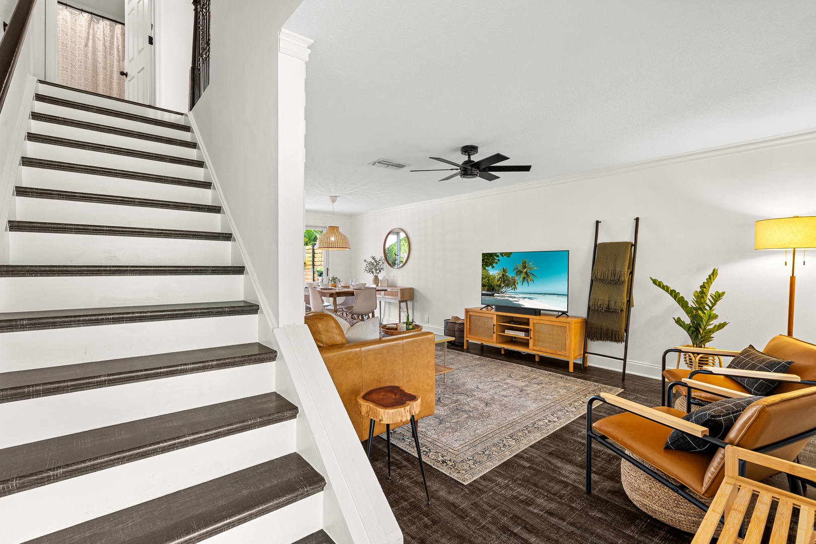 Unwind in your stylish living room, where modern comforts meet warm mid-century charm. Sink into plush seating, enjoy entertainment on the large TV, and feel the coastal breeze from the ceiling fan overhead.