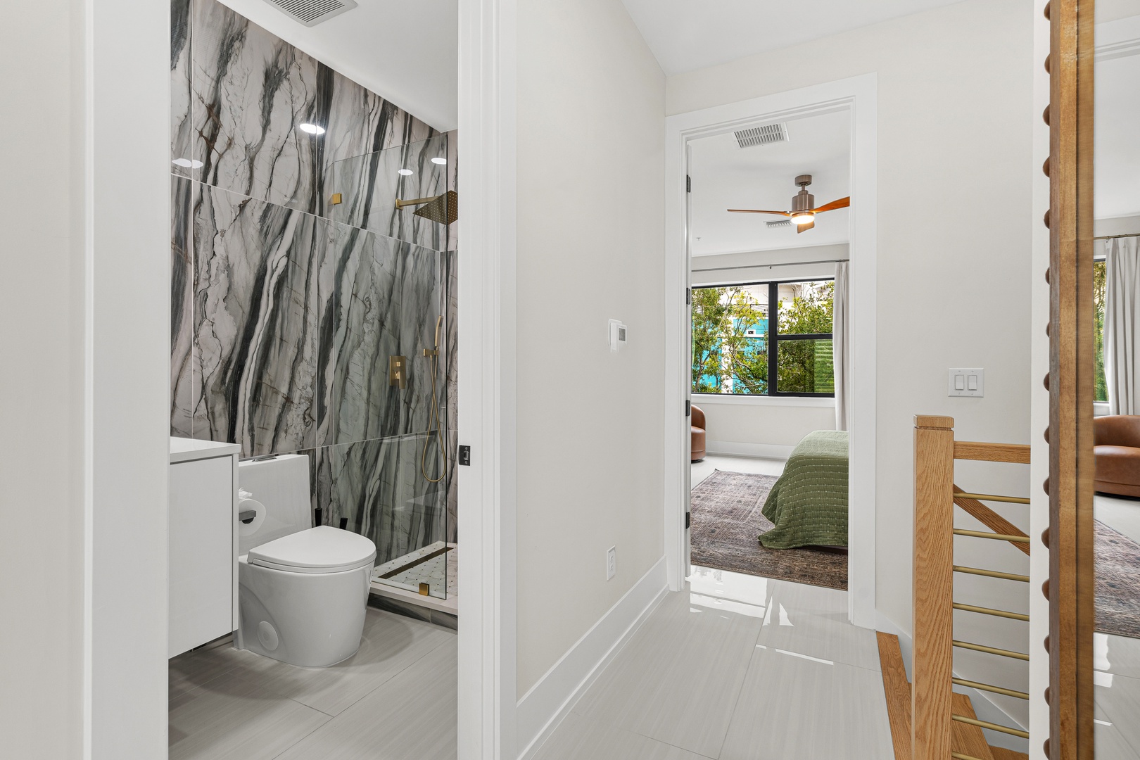 Step into your private escape—a sleek bathroom with dramatic marbled tile flows seamlessly into a sun-filled bedroom offering peaceful garden views beyond.