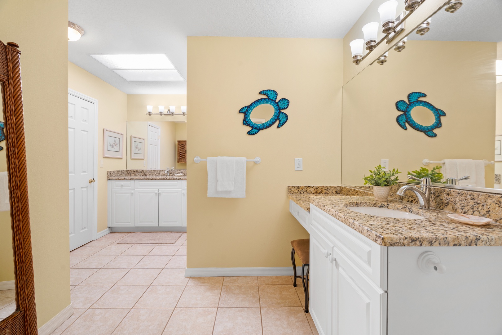 Step into your spacious master bathroom featuring dual granite vanities, warm coastal decor, and cheerful turtle artwork that sets a relaxing vacation mood.