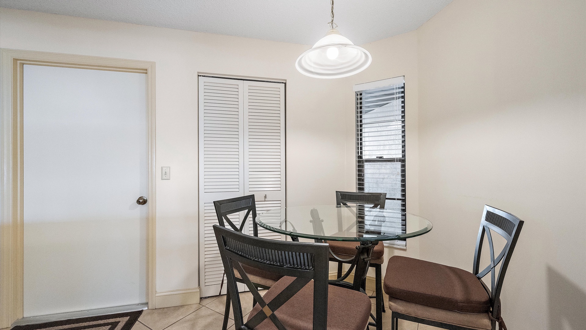 A bright dining spot where you'll enjoy morning coffee or evening meals around this glass table, with natural light streaming through the window and storage nearby for all your needs.