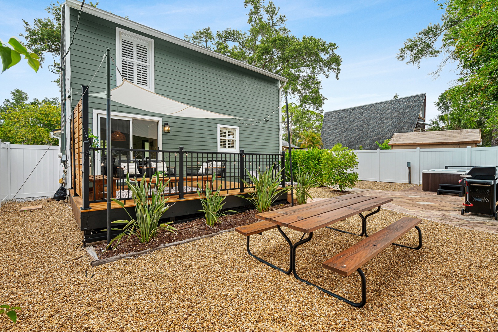 A charming outdoor retreat awaits with a spacious deck, picnic table for alfresco dining, hot tub for evening soaks, and a grill ready for your cookouts—all nestled in a peaceful, tree-lined backyard.