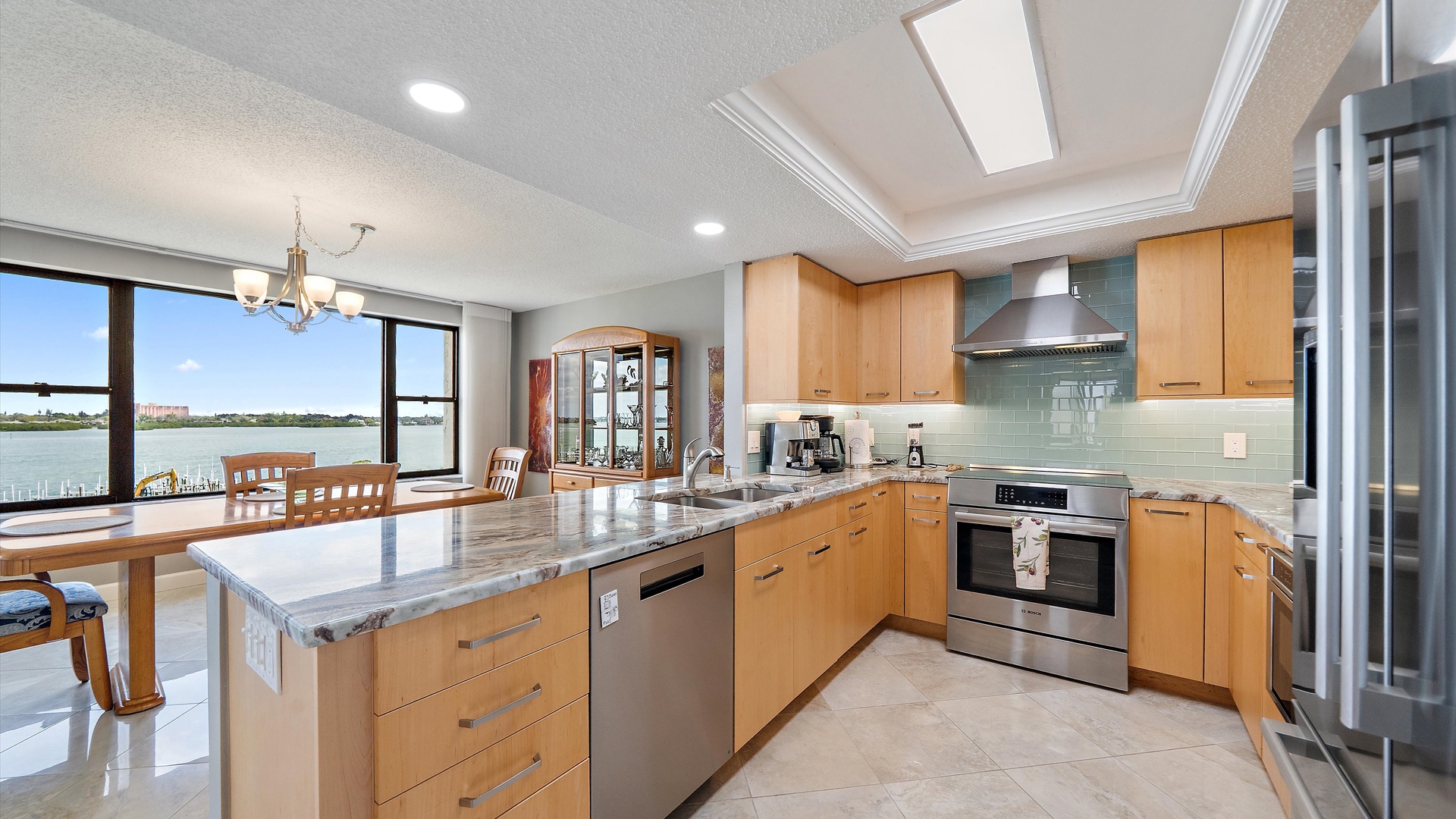 Your gourmet kitchen awaits with granite counters, stainless appliances, and stunning water views through floor-to-ceiling windows.