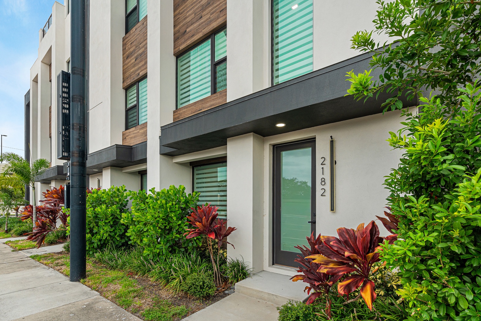 Modern townhome entrance featuring contemporary architecture and tropical plantings.