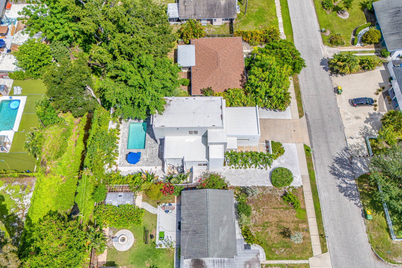 Aerial view of a residential property nestled in a lush, tree-lined neighborhood with a private pool and spacious outdoor areas.