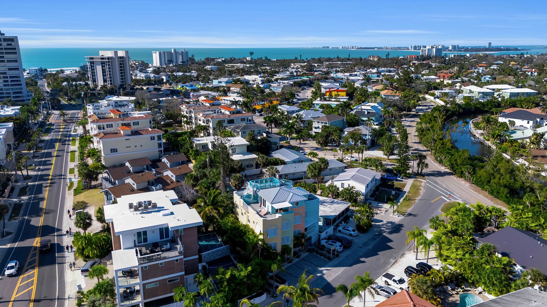 Aerial view of a coastal residential neighborhood with palm-lined streets, showing the property's proximity to the beach and surrounding community. Enjoy easy access to waterfront living and local conveniences.