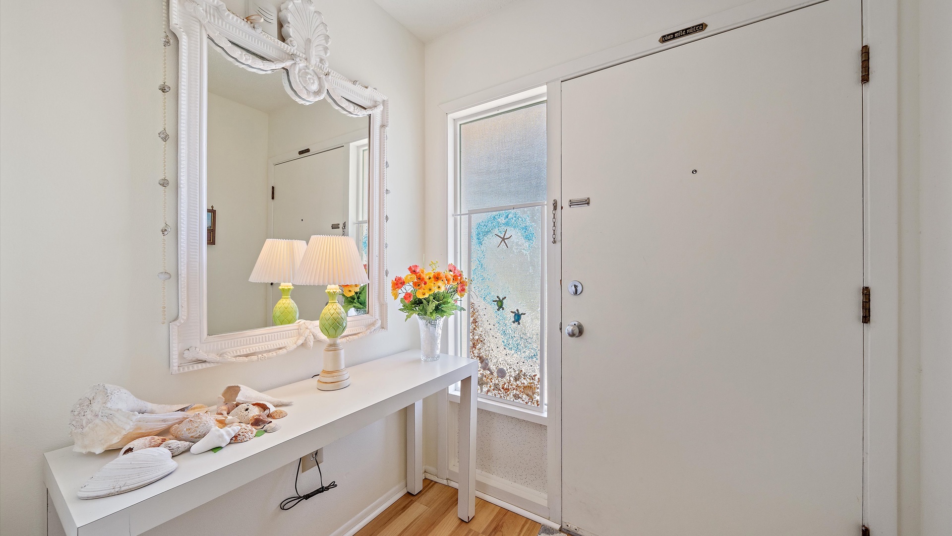 Step into your bright, welcoming entryway where coastal charm meets thoughtful comfort. A fresh floral arrangement and soft lighting greet you at the door.